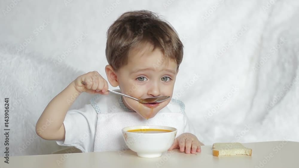 Boy child eating soup with a spoon Boy child eating soup with a spoon