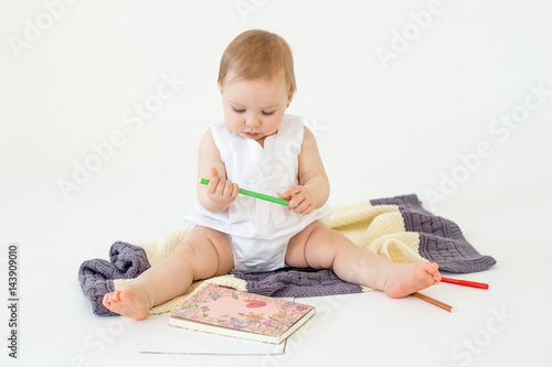 Baby girl sitting on floor near markers and colouring