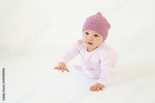 Little baby girl wearing hat sitting on floor