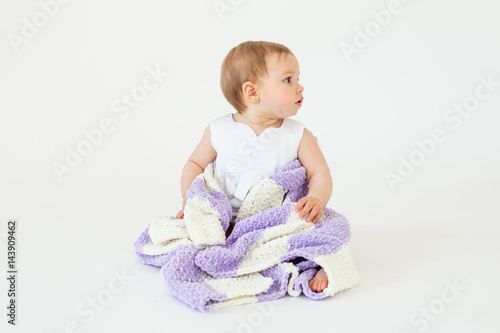 Pretty little baby girl sitting on floor with plaid isolated