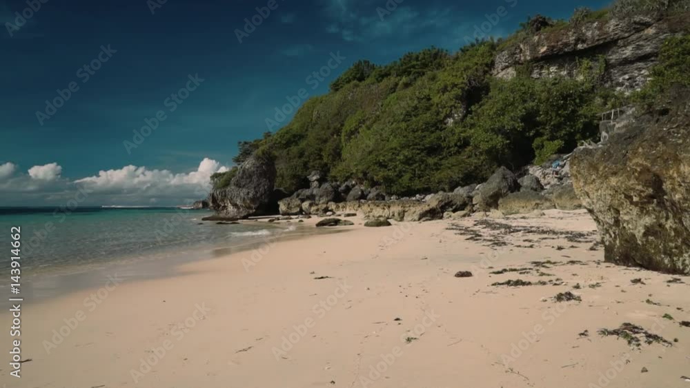 Clean white sand beach with rocks and cliffs and turquoise water - Geger beach, Bali on sunny summer day. Shot with Sony a7s on slider Clean white sand beach with rocks and cliffs and turquoise water - Geger beach, Bali on sunny summer day. Shot with Sony a7s on slider