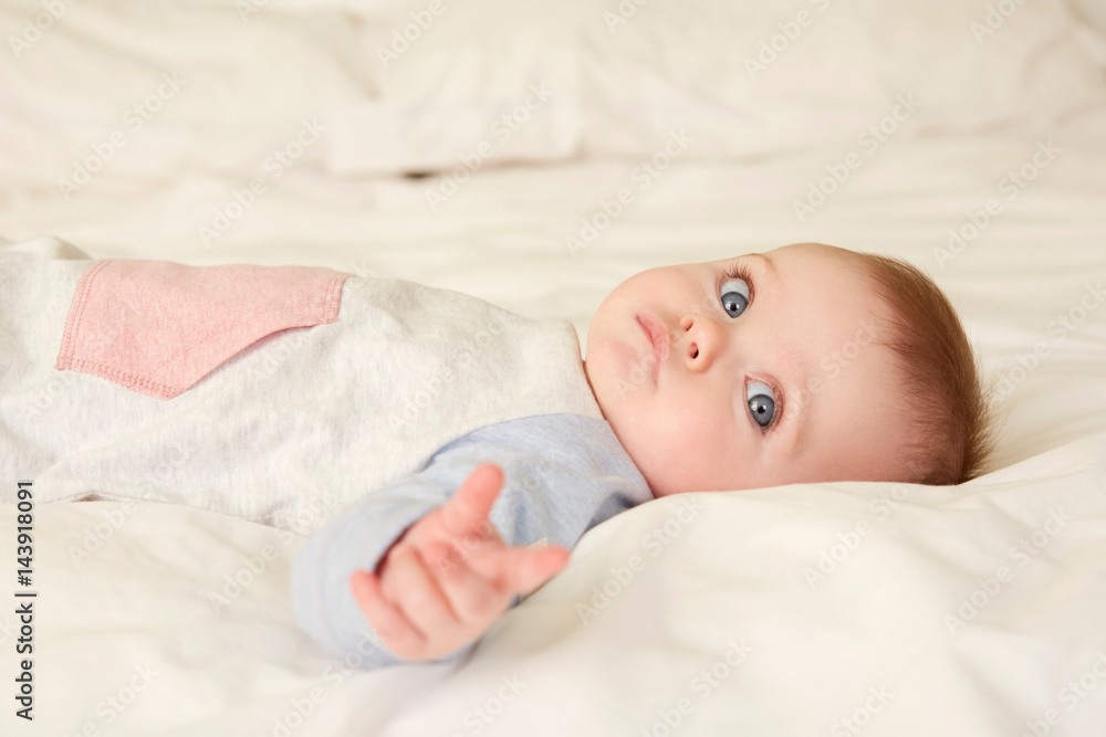 Portrait of blue eyed baby girl lying on bed Portrait of blue eyed baby girl lying on bed