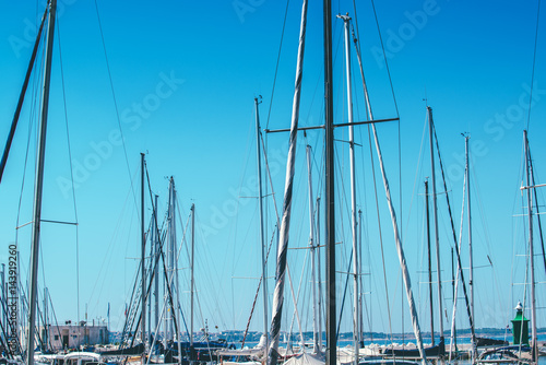 Sailboat masts in harbor against blue sky