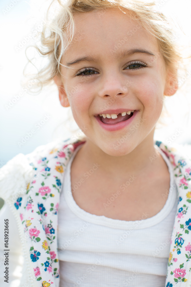 Portrait of cute blond girl with tooth missing at coast Portrait of cute blond girl with tooth missing at coast