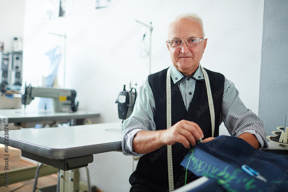 Modern tailor sewing clothes for his clients Modern tailor sewing clothes for his clients