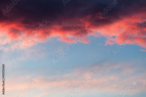 Fototapeta Naklejka Na Ścianę i Meble -  Beautiful sky background with dark blue, red stormy cloud at the top and light blue, pink sky at the bottom. Contrast pattern at sunset.