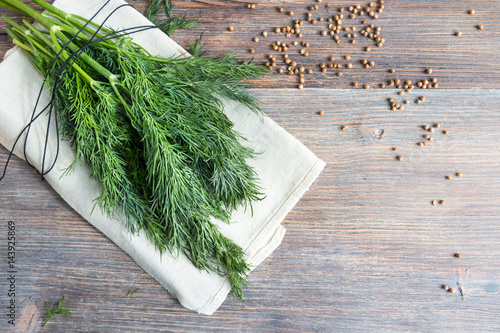 Bunch of fresh dill herbs and coriander seeds on wooden table, top view, copy space.