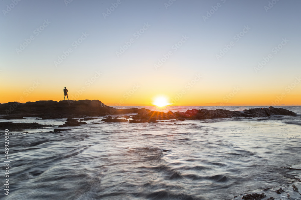 Fisherman silhouette at Currumbin Rock as the sunrises over the ocean