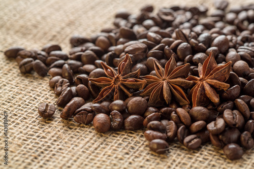 Coffee beans and illicium on a background of burlap. Roasted coffee beans background close up. Coffee beans pile from top with copy space for text. Seasoning. Spice. Badian. Coffee house.
