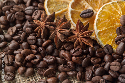 Coffee beans and illicium on a background of burlap. Roasted coffee beans background close up. Coffee beans pile from top with copy space for text. Seasoning. Spice. Badian. Coffee house.