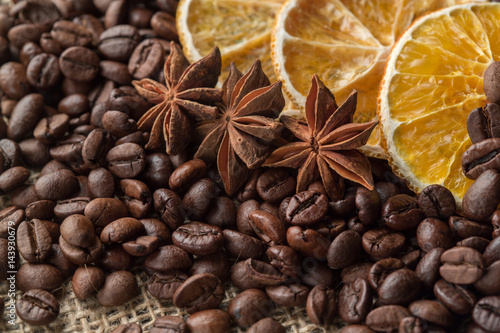 Coffee beans and illicium on a background of burlap. Roasted coffee beans background close up. Coffee beans pile from top with copy space for text. Seasoning. Spice. Badian. Coffee house.