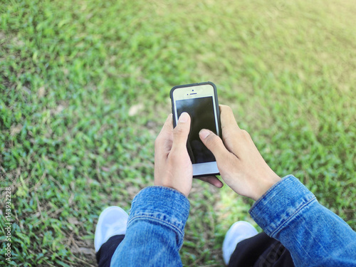 hand hold phone in morning green grass background