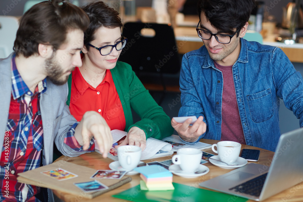 Portrait of three creative people smiling and discussing project while working at table in cafe during meeting Portrait of three creative people smiling and discussing project while working at table in cafe during meeting