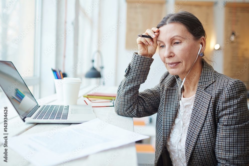 Modern businesswoman with earphones reading contract or resume Modern businesswoman with earphones reading contract or resume