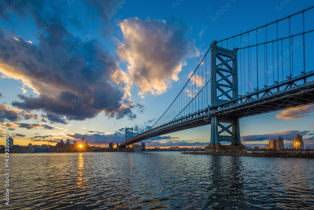 Fototapeta premium The Benjamin Franklin Bridge and and Delaware River at sunset, seen from Camden, New Jersey.