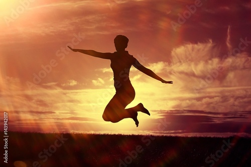 Silhouette of a girl against the sky jumping at sunset  concept of happiness
