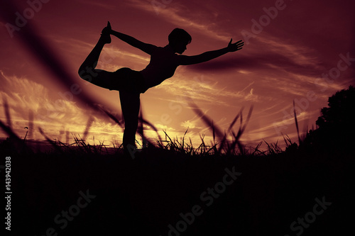 Silhouette of a young girl yoga pose sunset sport © kichigin19