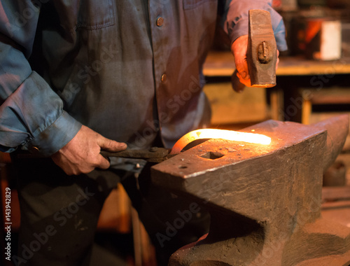 Making of horseshoe. Male worker with pliers and hammer making horseshoe.