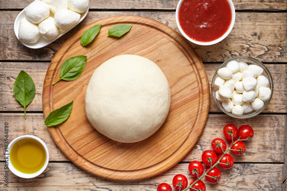 Pizza cooking ingredients: dough, mozzarella, tomatoes, basil, olive oil, cheese, sauce, spices. Work with the dough. Top view Flat lay. Italian food cuisine background pizza margherita preparation Pizza cooking ingredients: dough, mozzarella, tomatoes, basil, olive oil, cheese, sauce, spices. Work with the dough. Top view Flat lay. Italian food cuisine background pizza margherita preparation