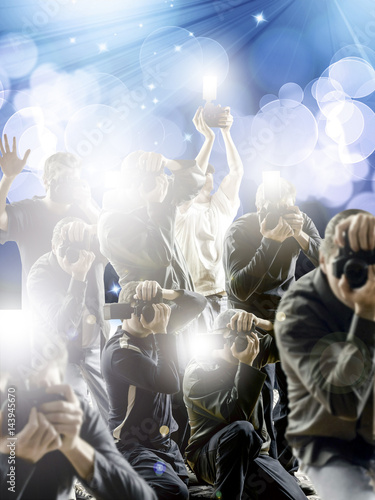 Crowd of paparazzi with flashing cameras in front a flashy background