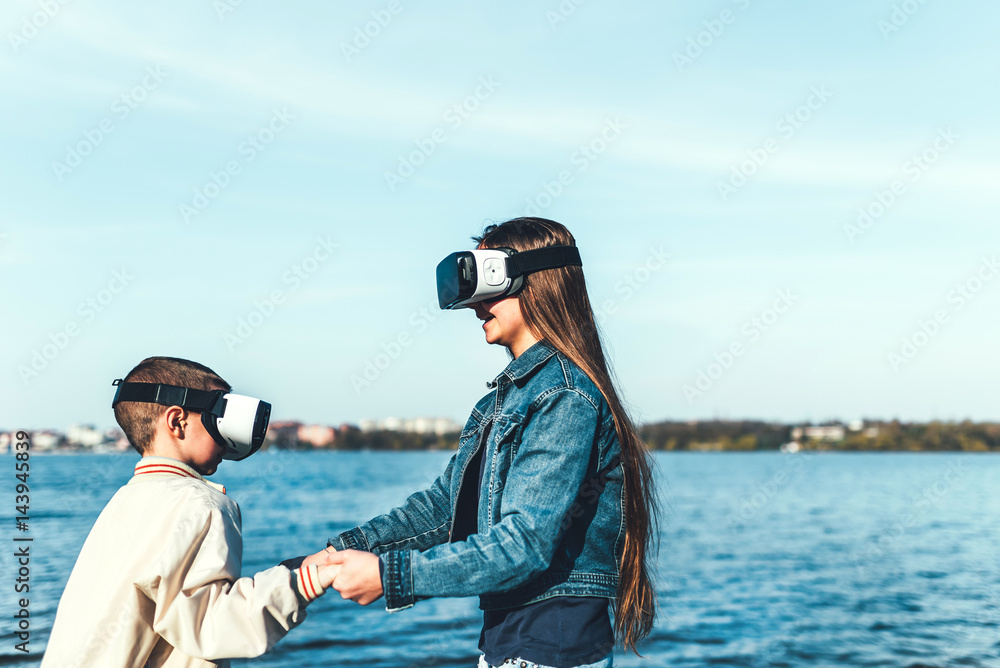 Sister with her little brother playing in VR glasses