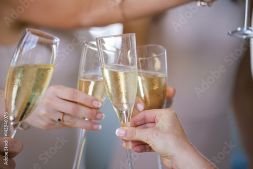Close up of champagne glasses being chimed together during a toast by a bride and her bridesmaids.