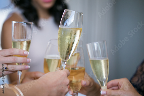 Close up of champagne glasses being chimed together during a toast by a bride and her bridesmaids.