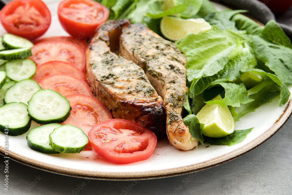 Baked salmon in a lemon-honey dressing with herbs served with fresh vegetables and salad 
