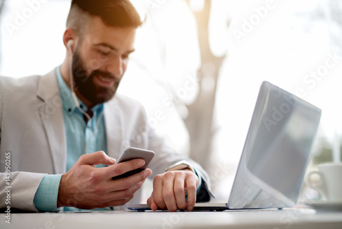 Принти на полотні Side view of man in suit checking emails on smart watch.