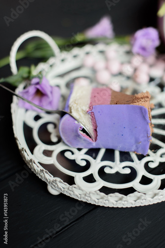 Piece of blueberry pie take with spoone near flowers on black wooden background photo