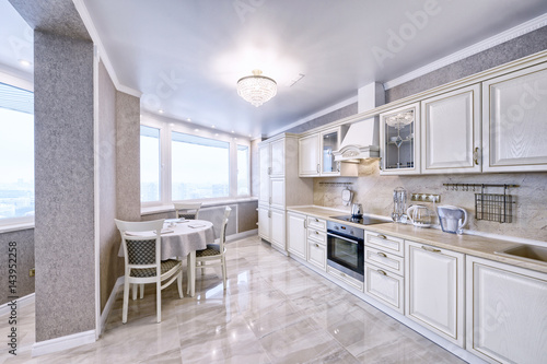 Interior of white wooden kitchen in a spacious apartment in light colors.