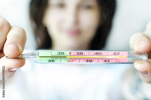 The girl holds a medical thermometer in her hands, showing the temperature of a healthy person