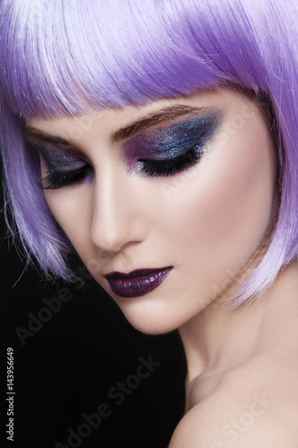 young beautiful woman with colorful fancy make-up and violet wig