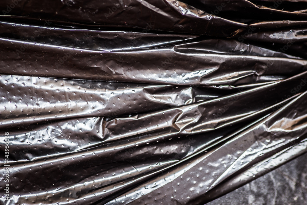 Close-up fragment of a crumpled black polyethylene trash bag Close-up fragment of a crumpled black polyethylene trash bag
