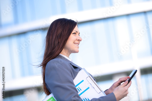 Businesswoman working on digital tablet outdoor over building background photo