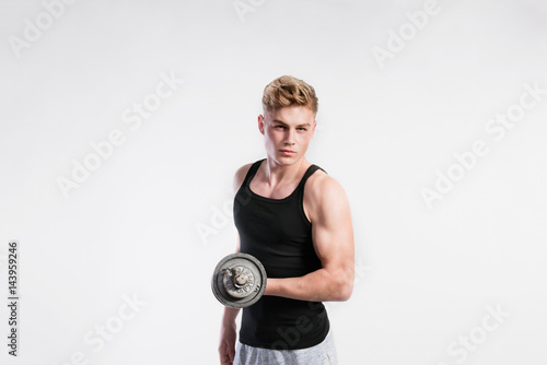 Handsome fitness man holding dumbbell, studio shot.