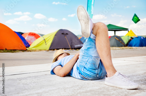Unrecognizable on summer music festival, lying on concrete path.