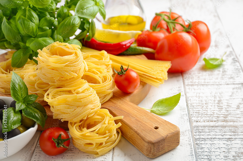 Pasta, vegetables, herbs and spices for Italian food on white wooden background, selective focus