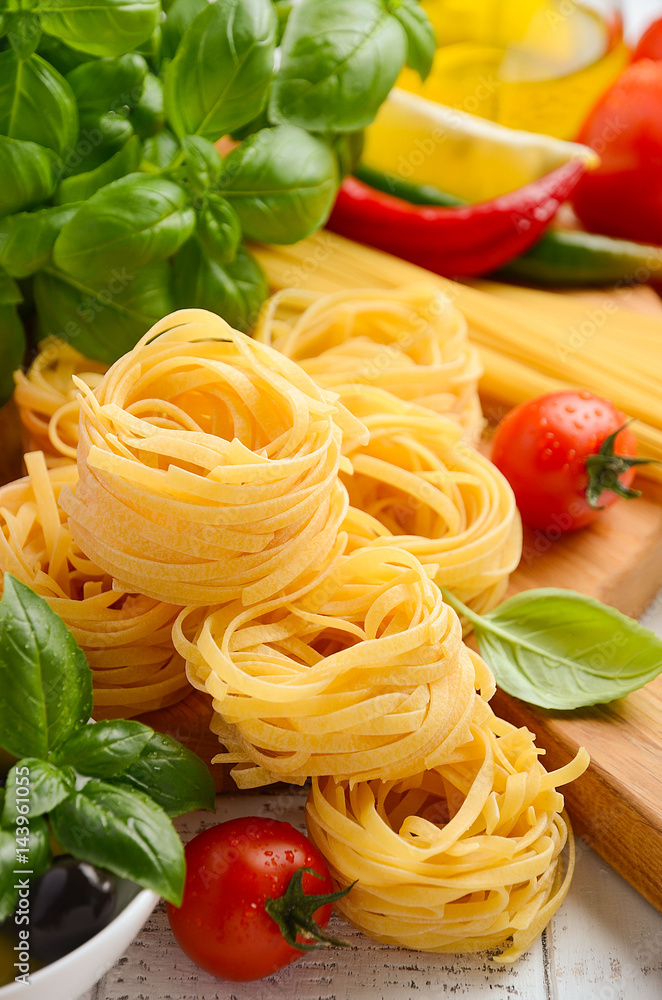 Pasta, vegetables, herbs and spices for Italian food on white wooden background, selective focus Pasta, vegetables, herbs and spices for Italian food on white wooden background, selective focus