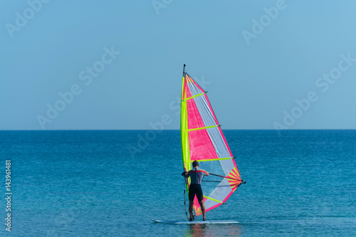 Windsurfer man windsurfing on board with sail in sea