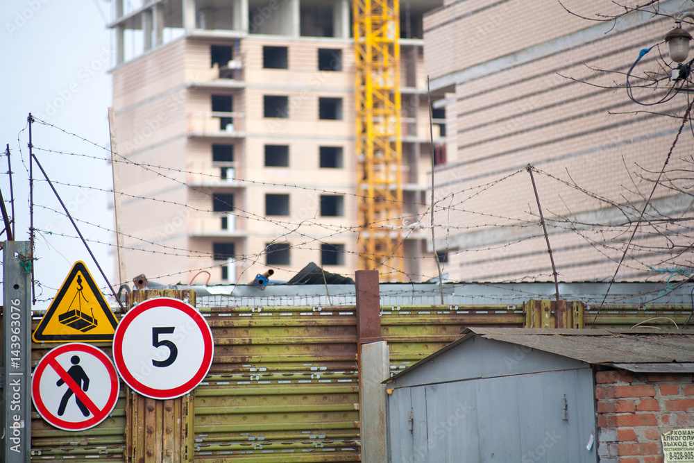 Building crane at the background of a multi-storey building under construction