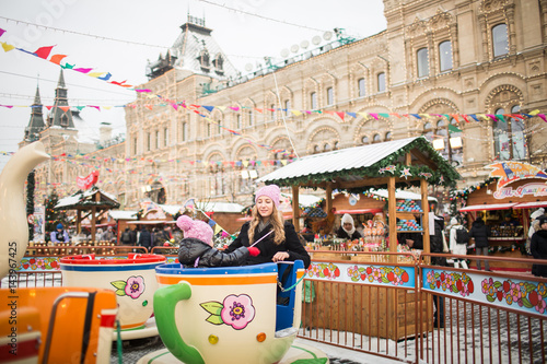 Mom and daughter are riding an attraction at market © yuliasverdlova