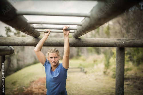 Fit woman climbing horizontal bars during obstacle course