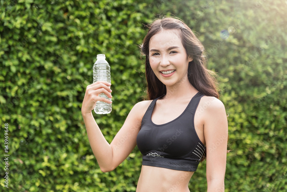 Asian woman in sportswear holding bottle of water on natural background. freshness, happiness, relaxing and smiling. Asian woman in sportswear holding bottle of water on natural background. freshness, happiness, relaxing and smiling.