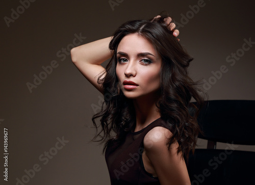Sexy young makeup model in brown dress posing on dark shadow background and looking passion