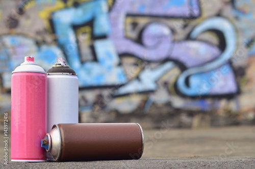 A still-life of several used paint cans of different colors against the graffiti wall