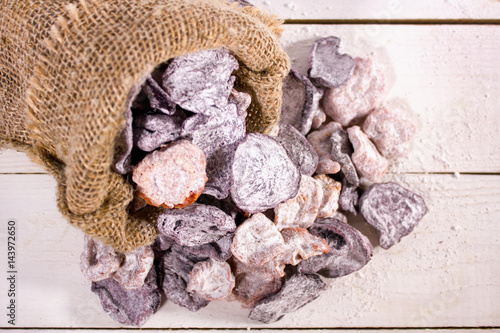Tasty candied fruits and vegetables in the sack on white wooden background