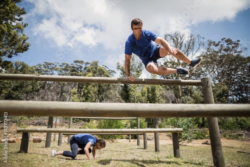 Obraz w ramie Man and woman jumping over the hurdles during obstacle course