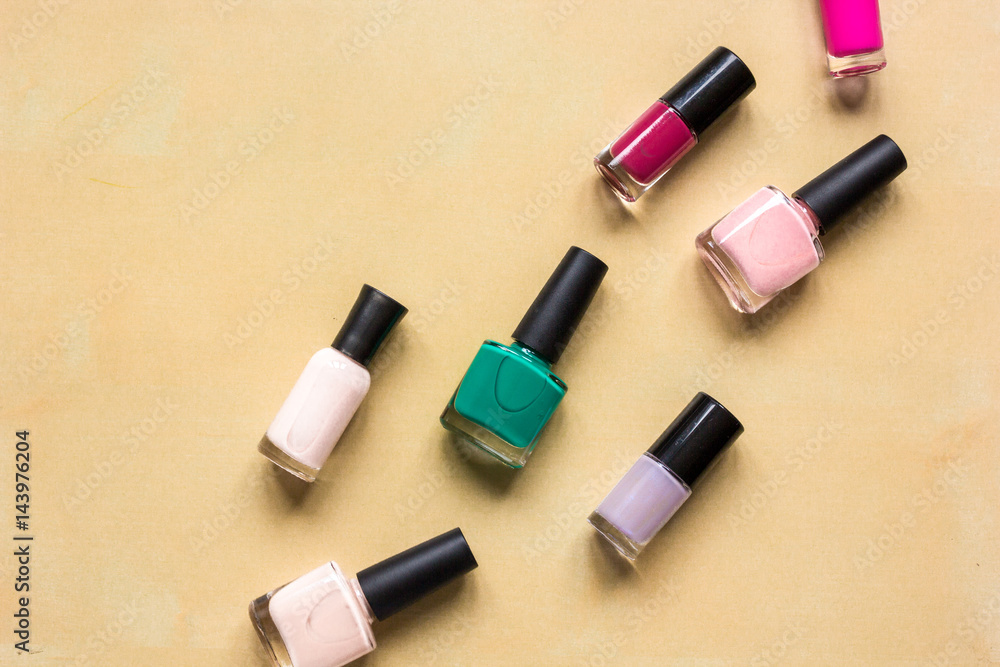 Obraz premium Bottles with nail polish over orange background top view mockup