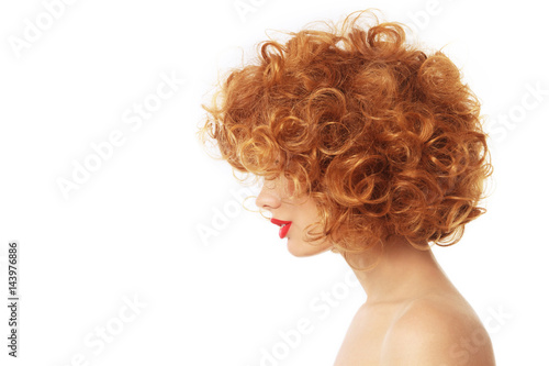 Profile portrait of young woman with beautiful red curly hair over wite background, copy space
